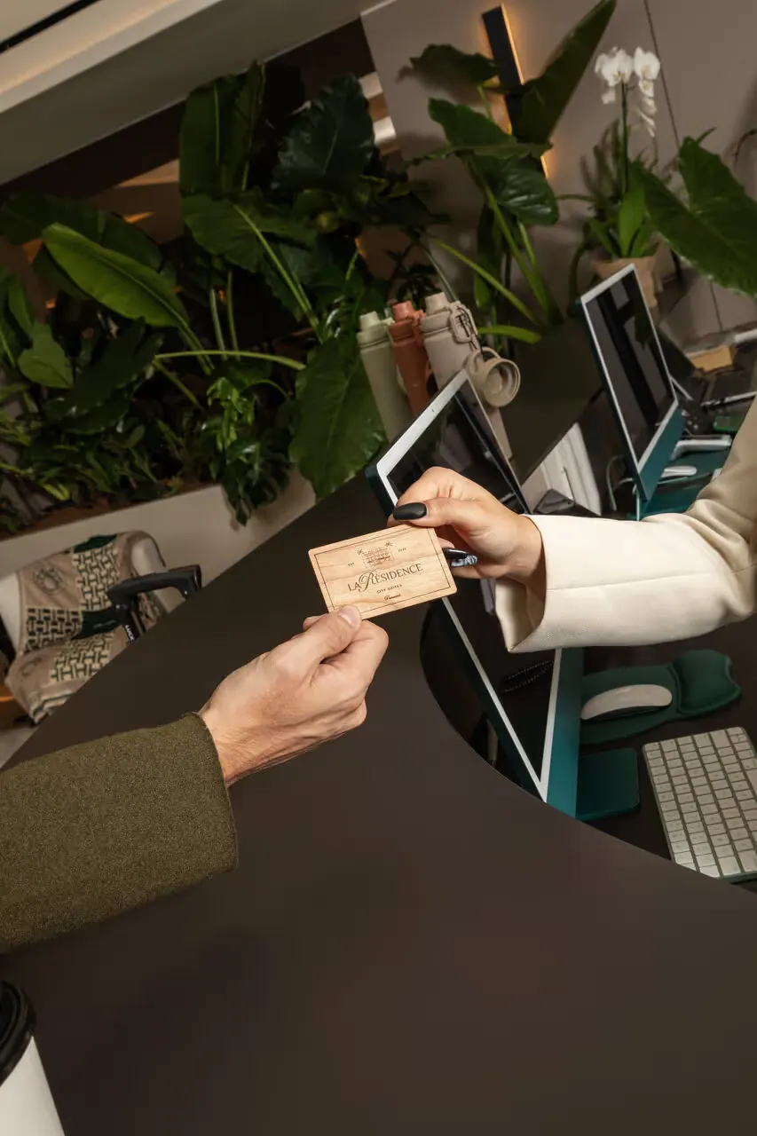Hands passing a room card at the reception desk.